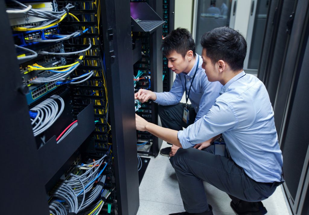 two people working on a server in a data center
