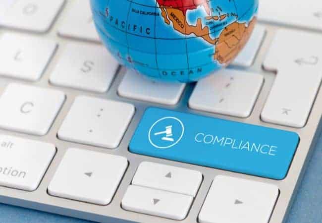 a globe sitting on a keyboard with the word compliance on it