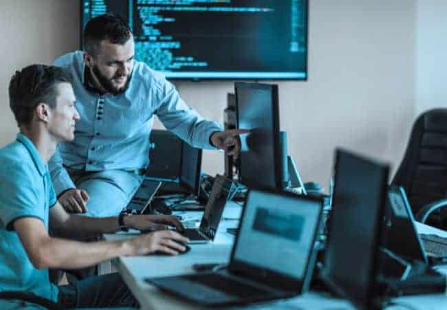 two people working on computers in an office