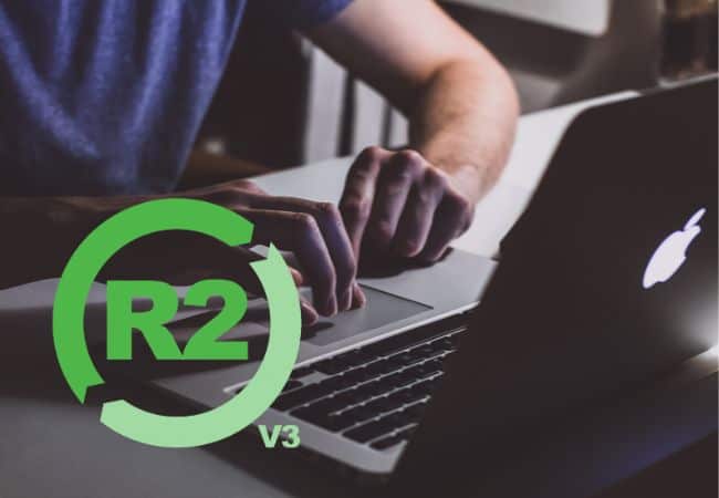 a person’s hands typing on a macbook keyboard with an r2v3 logo