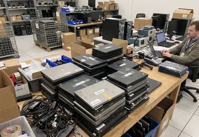 technician with stacks of laptops to process